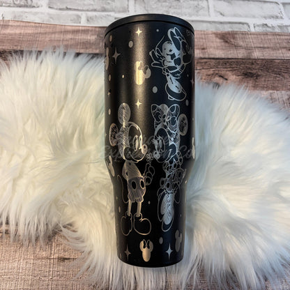 A black tumbler mug with a Disney-themed design featuring Mickey Mouse and Minnie Mouse characters.