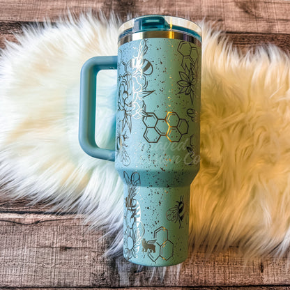 A turquoise insulated tumbler mug with a handle and lid, placed on a white furry surface.