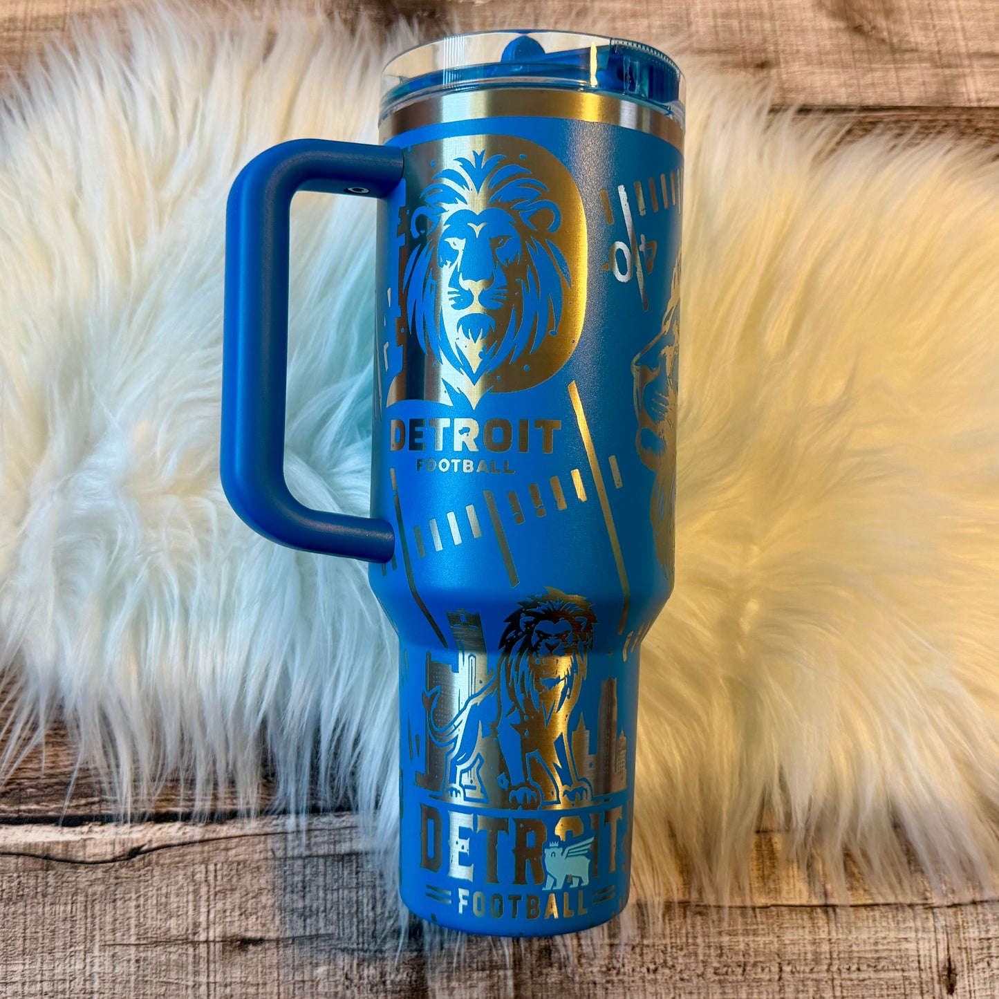 A blue insulated tumbler mug with a handle and a lid, featuring the logo and design of the Detroit Football team.