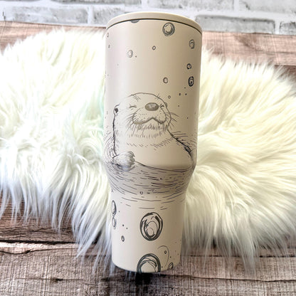 A white ceramic mug with a black and white illustration of an otter or seal on it, placed on a white fur rug.