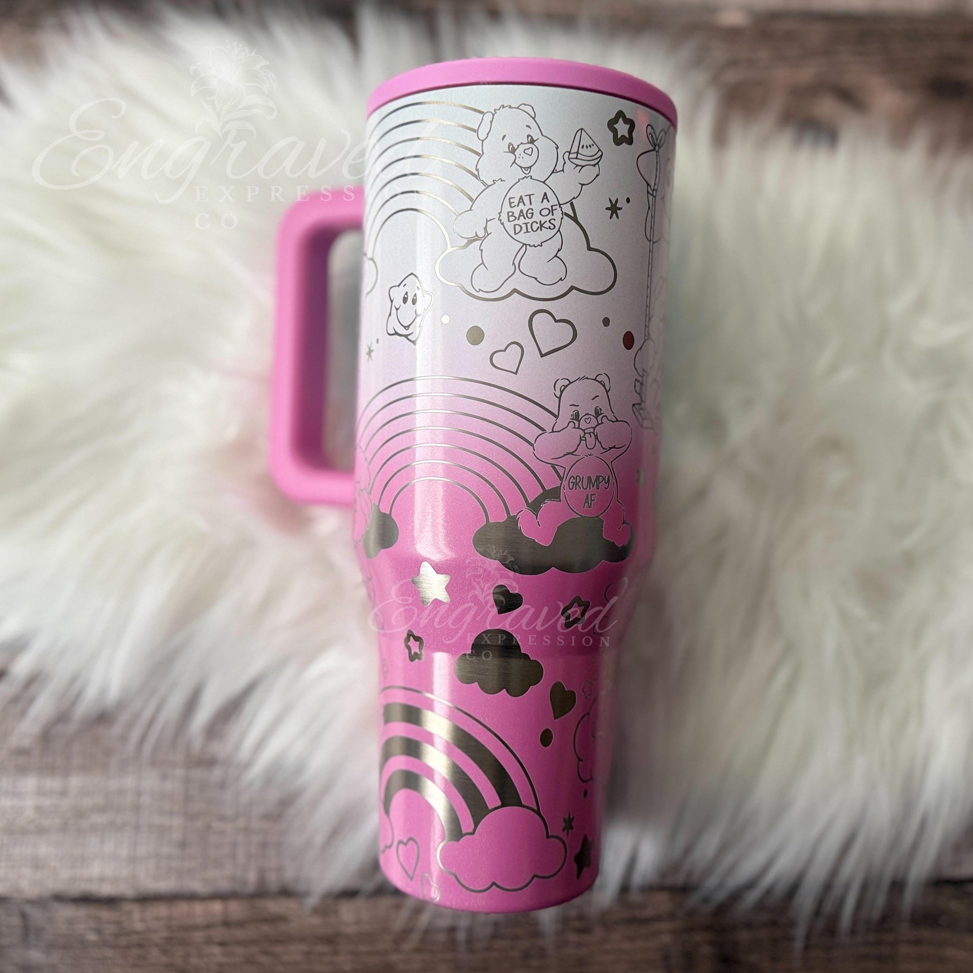 A pink and white tumbler mug with a whimsical design featuring a pink bear, clouds, rainbows, and stars.