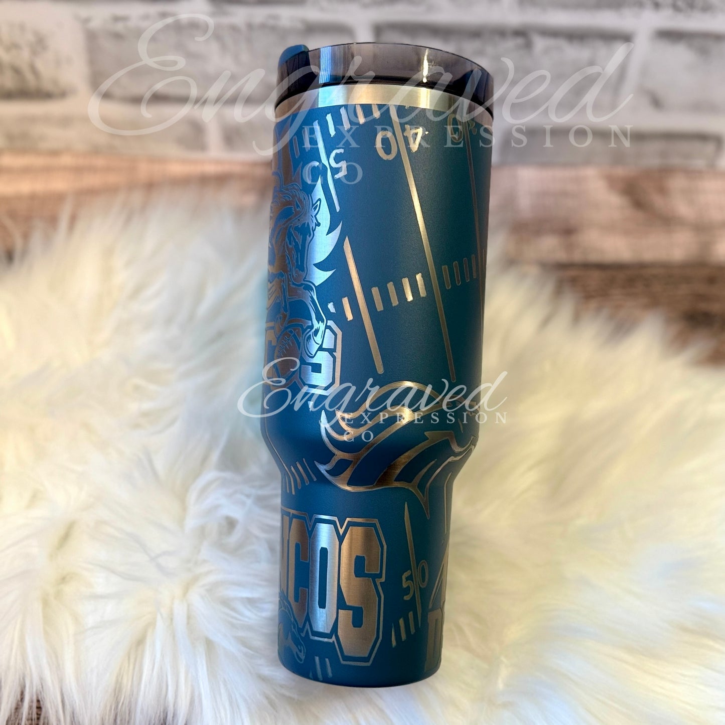 A blue tumbler with a unique design featuring a football field pattern and the word "TOS" printed on it.
