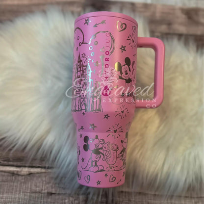 A pink tumbler mug with a Disney-themed design, featuring Mickey Mouse and other Disney characters, is placed on a white fur surface.