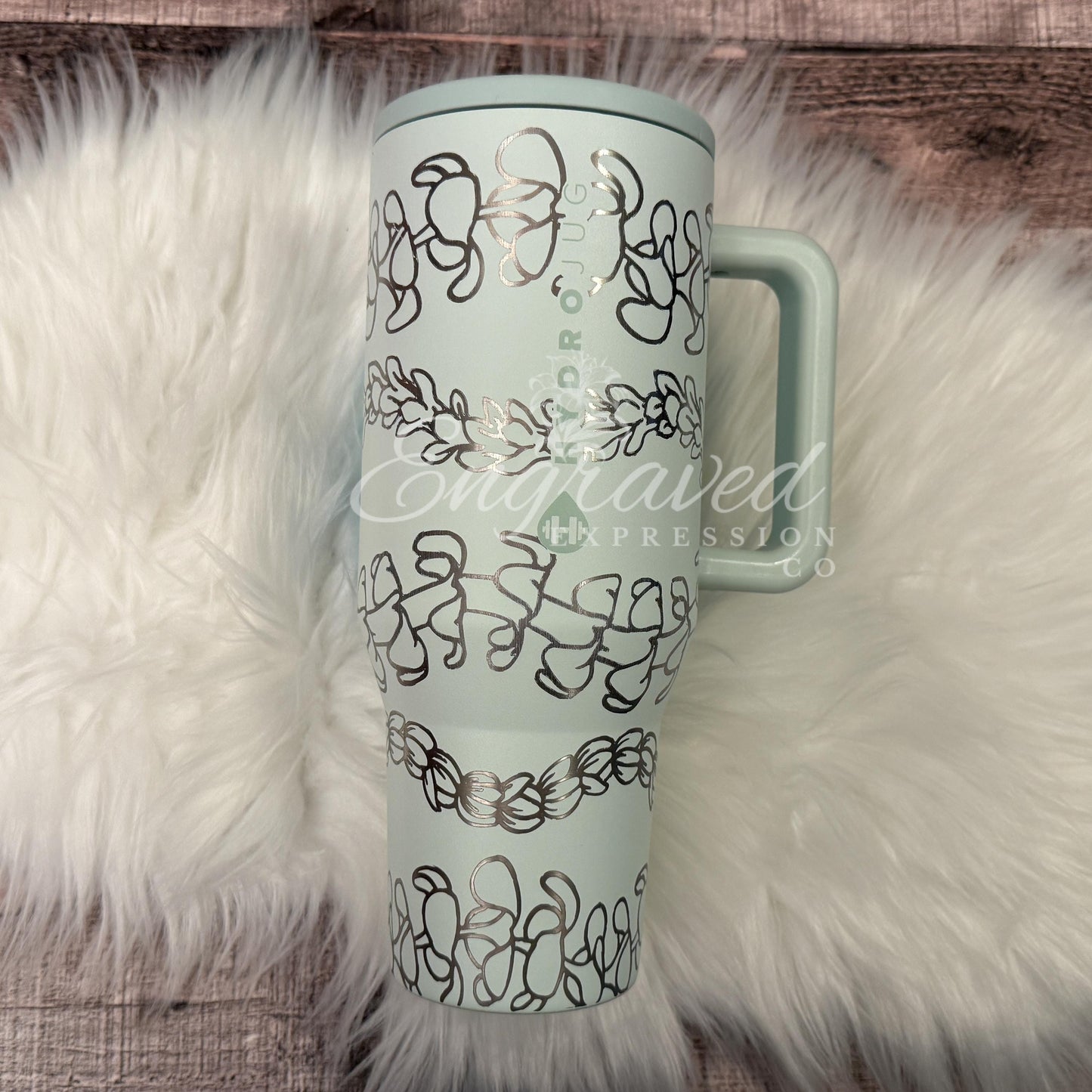 A turquoise insulated tumbler mug with a handle, placed on a white furry surface.